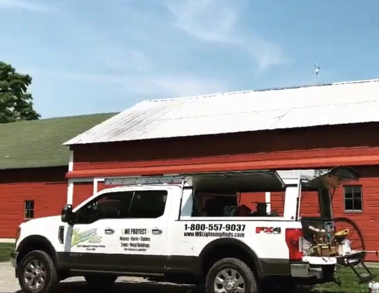 WB Lightning Rods work truck parked in front of red farm barns on a New York dairy farm