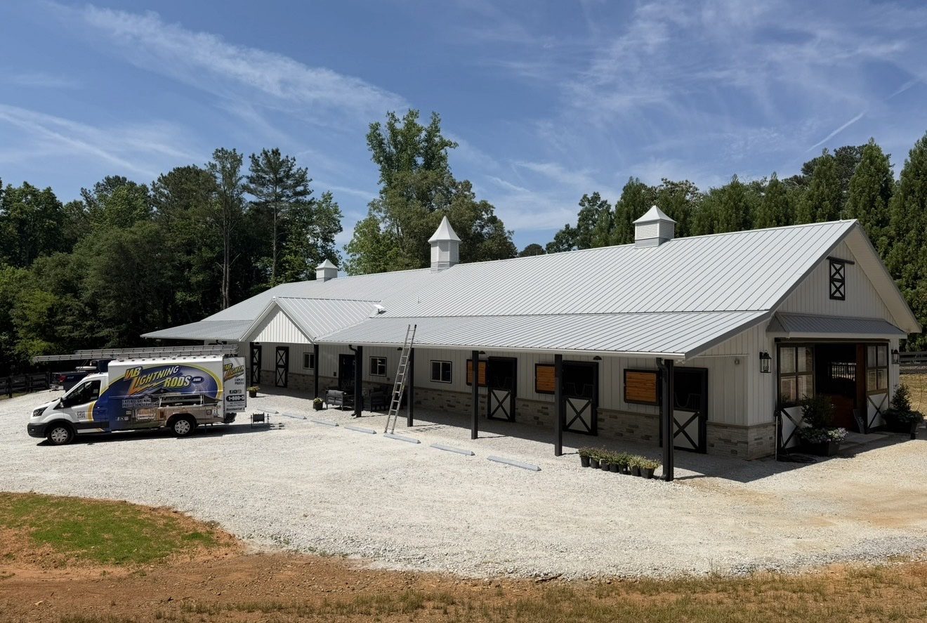WB Lightning Rods van parked in front of an elegant white horse stable with cupolas